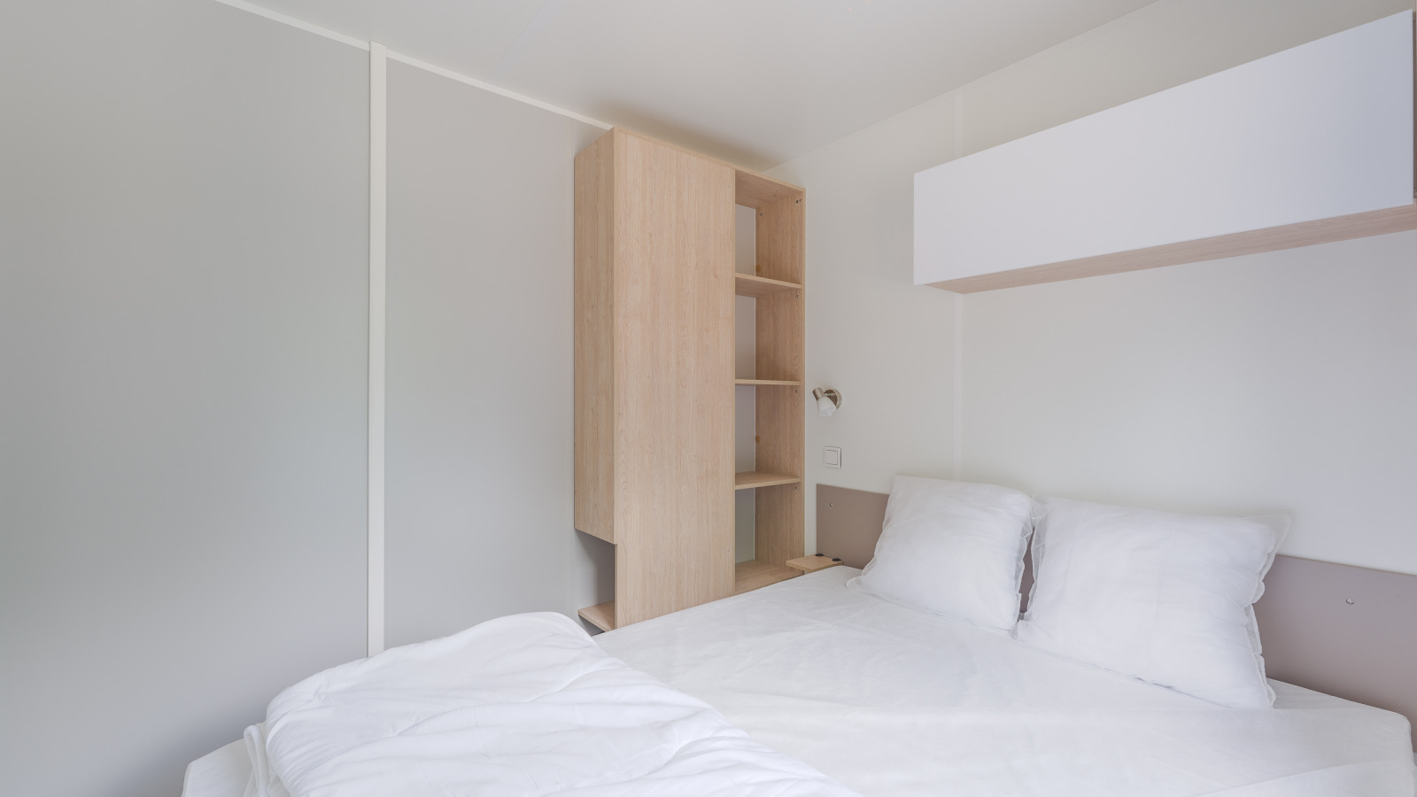 Modern, minimalistisch interieur van een cottage op Camping Seasonova du Chêne in Frankrijk, met bed en kast.