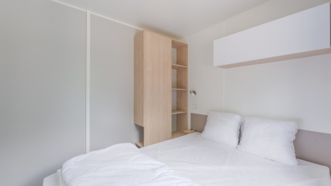 Interior moderno y minimalista de una cabaña en Camping Seasonova du Chêne, Francia, con cama y armario.