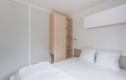 Interior moderno y minimalista de una cabaña en Camping Seasonova du Chêne, Francia, con cama y armario.