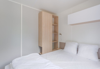Interior moderno y minimalista de una cabaña en Camping Seasonova du Chêne, Francia, con cama y armario.