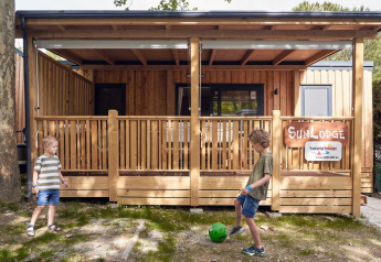 Deux enfants jouent au ballon devant un lodge SunLodge Katsura au Camping Gasparina en Italie.