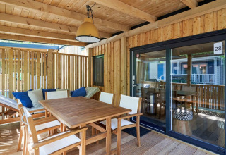 Terraza de madera cubierta en SunLodge Katsura, Camping Gasparina, Italia, con mesa de comedor y sillas cómodas.