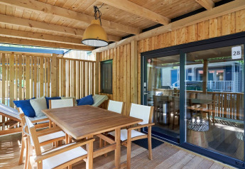 Terrasse en bois couverte à SunLodge Katsura, Camping Gasparina, Italie, équipée d’une table et de chaises.