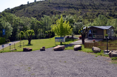 Vue du Camping Saint Amand en Auvergne-Rhône-Alpes, France, avec pelouse verdoyante et bâtiment d'accueil.