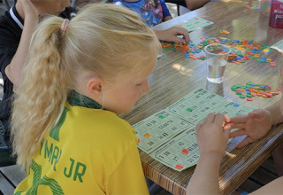 Kinder spielen Bingo mit bunten Chips an einem Tisch im Camping Saint Amand in Auvergne-Rhône-Alpes, Frankreich.