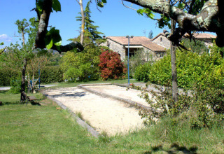 Outdoor sand court at Camping Saint Amand in Auvergne-Rhône-Alpes, surrounded by trees, plants and cottages.