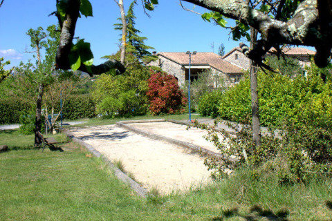 Outdoor sand court at Camping Saint Amand in Auvergne-Rhône-Alpes, surrounded by trees, plants and cottages.