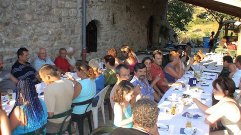 Group of people sharing an outdoor meal at a long table at Camping Saint Amand, Auvergne-Rhône-Alpes, France.