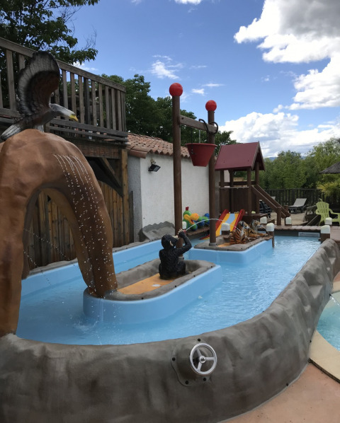 Area giochi d’acqua al Camping Saint Amand, Auvergne-Rhône-Alpes, Francia, con statue e scivoli per bambini.