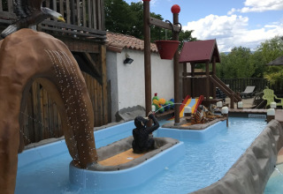 Area giochi d’acqua al Camping Saint Amand, Auvergne-Rhône-Alpes, Francia, con statue e scivoli per bambini.