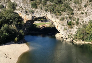 Kajakker på en flod med en naturlig stenbue i baggrunden, campingferie ved Saint Amand, Auvergne-Rhône-Alpes.