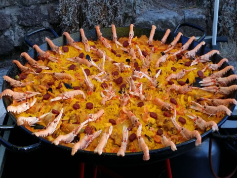 A large pan filled with paella garnished with prawns and seafood, taken at Camping Saint Amand in France.