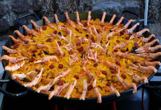 En stor pande fyldt med paella pyntet med rejer og skaldyr, fotograferet på Camping Saint Amand i Frankrig.