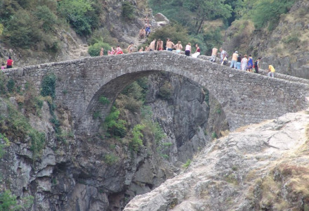 Persone camminano su un antico ponte di pietra vicino a Laurac-en-Vivarais, Auvergne-Rhône-Alpes, Francia.