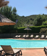 Udendørs swimmingpool med liggestole og stråparasoller ved Camping Saint Amand i Auvergne-Rhône-Alpes, Frankrig.