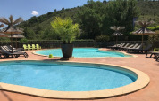 Udendørs swimmingpool med liggestole og parasoller på Camping Saint Amand i Auvergne-Rhône-Alpes, Frankrig.