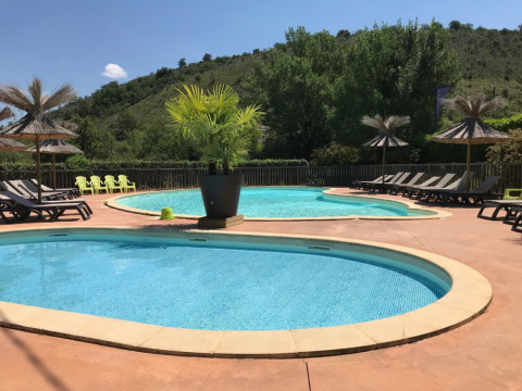 Outdoor swimming pool with loungers and parasols at Camping Saint Amand in Auvergne-Rhône-Alpes, France.