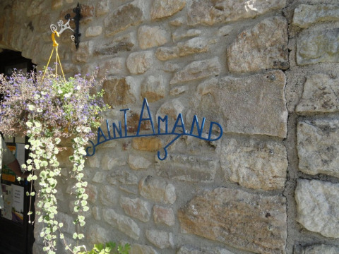Entrada al Camping Saint Amand con una maceta colgante y pared de piedra, Auvernia-Ródano-Alpes, Francia.