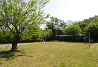 Buitenvolleybalveld bij Camping Saint Amand met gras en bomen in Auvergne-Rhône-Alpes, Frankrijk.