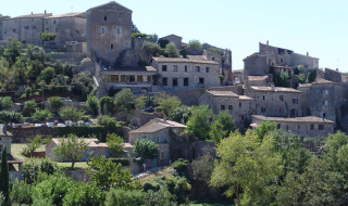 Vista delle storiche case in pietra e del verde lussureggiante di Laurac-en-Vivarais, Auvergne-Rhône-Alpes.