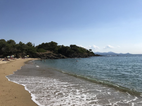 Vista de la playa en Camping Les Lauriers Roses en Provence-Alpes-Côte d’Azur, Francia, con bañistas y sombrillas.