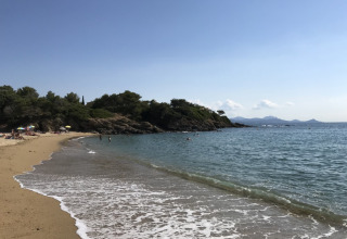 Strandblick beim Camping Les Lauriers Roses in Provence-Alpes-Côte d’Azur, Frankreich, mit Badegästen und Felsen.