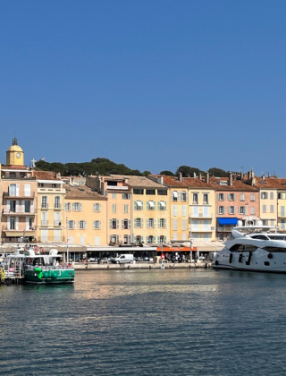 Farverig havnefront i Provence-Alpes-Côte d’Azur, Frankrig, med lystbåde og pastelfarvede bygninger.