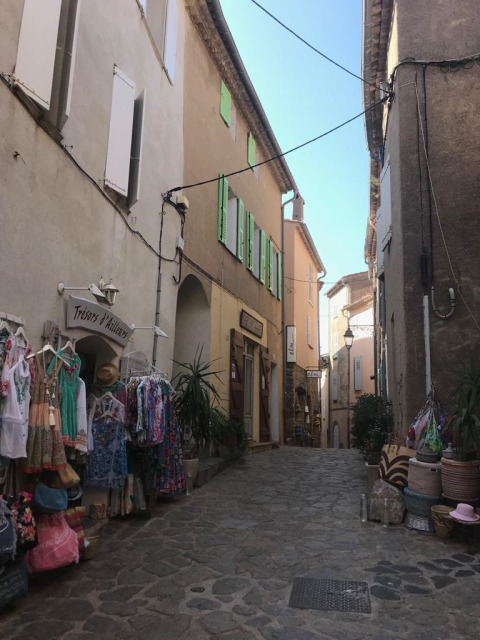 Un'affascinante strada acciottolata con negozi tipici e mercanzie colorate in Provenza, Francia.