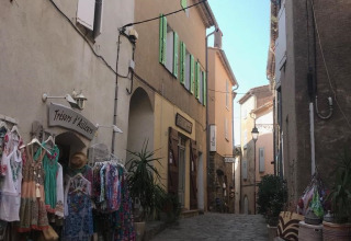 En charmerende brostensgade med butikker og farverige varer i Provence-Alpes-Côte d’Azur, Frankrig.