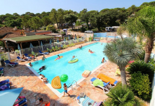 Outdoor swimming pool with people relaxing and swimming at Camping Les Lauriers Roses, Provence-Alpes-Côte d’Azur, France.