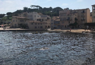 Seaside view from Camping Les Lauriers Roses with waterfront buildings and sparkling water in Provence, France.