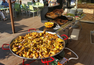 Stor udendørs buffet med grillmad og en kæmpe pande med kartofler og kylling på Camping Les Lauriers Roses.