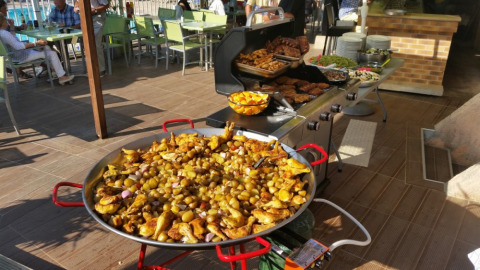 Groot buitenbuffet met gebraad en een grote pan met aardappelen en kip bij Camping Les Lauriers Roses.