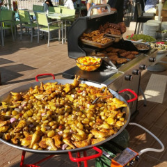 Stor udendørs buffet med grillmad og en kæmpe pande med kartofler og kylling på Camping Les Lauriers Roses.