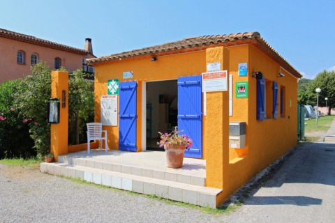 En farverig orangerød bygning med blå skodder ved Camping Les Lauriers Roses i Provence, Frankrig.