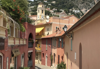 Strada tranquilla con edifici colorati e vista collinare, scattata al Camping Les Lauriers Roses nel sud della Francia.