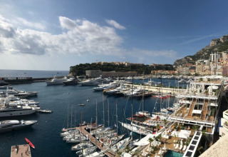 Blick auf einen Yachthafen mit vielen Booten, einer Stadt und Bergen in Provence-Alpes-Côte d’Azur, Frankreich.