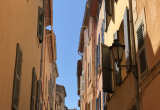 Stradina stretta con edifici dai colori pastello e persiane in Provenza-Alpi-Costa Azzurra, Francia.