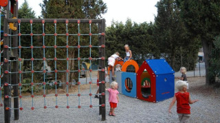 Børn leger på legepladsen med klatrestativ og legehus i Camping Les Lauriers Roses, Provence-Alpes-Côte d’Azur.