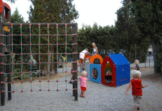 Kinder spielen auf einem Spielplatz mit Klettergerüst und Spielhaus im Camping Les Lauriers Roses in Frankreich.