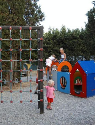 Børn leger på legepladsen med klatrestativ og legehus i Camping Les Lauriers Roses, Provence-Alpes-Côte d’Azur.