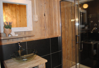 Salle de bain sous tente safari au Camping Roland aux Pays-Bas avec vasque en verre et cabine de douche.