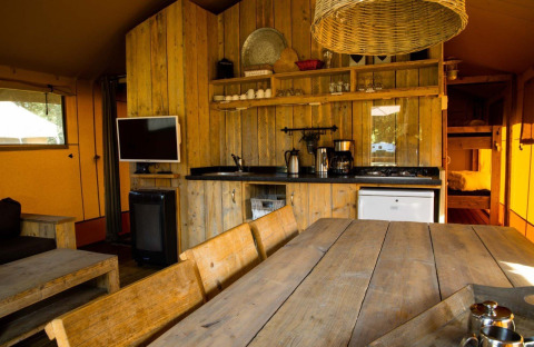 Rústica tienda safari en Camping Roland, Países Bajos, con muebles de madera y zona de cocina.