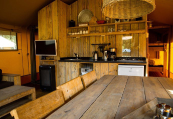 Rustik safaritelthytte på Camping Roland i Holland med træmøbler og køkkenudstyr i interiøret.