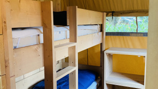 Interieur van een safaritent met houten stapelbedden bij Familiepark Goolderheide in België.