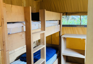 Interior view of a safari tent with wooden bunk beds and shelving at Familiepark Goolderheide in Belgium.