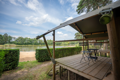 Udsigt fra Duo Lodge ved Familiepark Goolderheide i Belgien med veranda og sø i baggrunden.