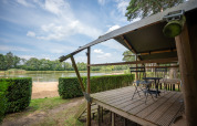 Udsigt fra Duo Lodge ved Familiepark Goolderheide i Belgien med veranda og sø i baggrunden.
