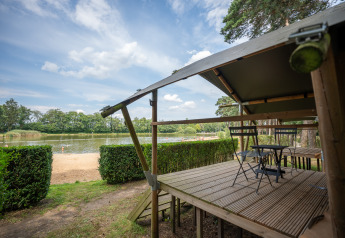 Udsigt fra Duo Lodge ved Familiepark Goolderheide i Belgien med veranda og sø i baggrunden.