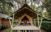 Un Duo Lodge au Familiepark Goolderheide en Belgique, situé parmi les arbres avec terrasse et chaises de camping.